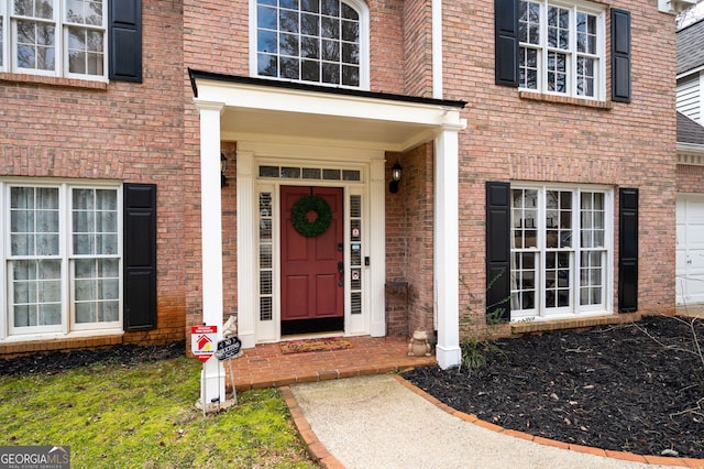 property entrance featuring a garage and brick siding