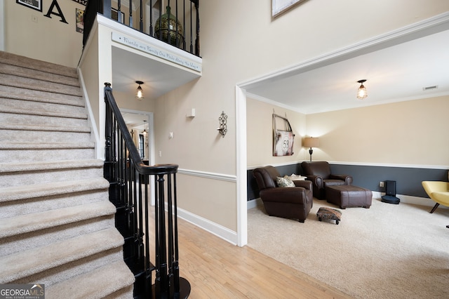 staircase with ornamental molding, visible vents, and baseboards