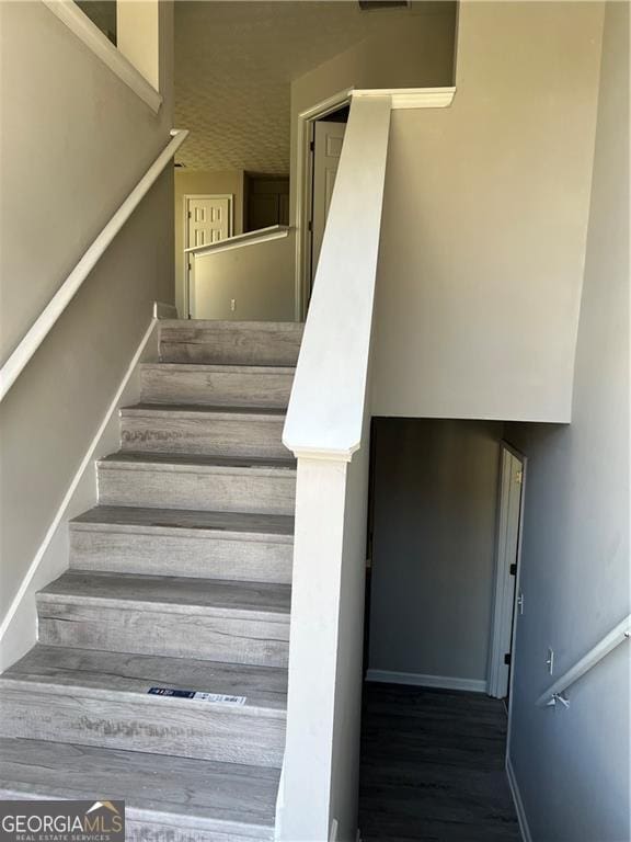 staircase featuring baseboards and wood finished floors