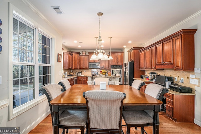 dining space with light wood-type flooring, crown molding, baseboards, and recessed lighting