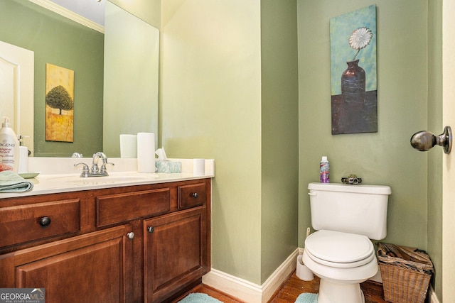 half bath with wood finished floors, vanity, toilet, and baseboards