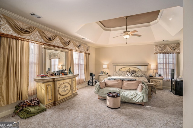 bedroom with carpet floors, a raised ceiling, visible vents, and crown molding