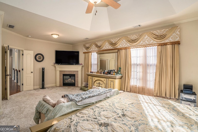 bedroom featuring crown molding, a tiled fireplace, visible vents, and carpet flooring