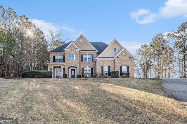 traditional home with brick siding, a front lawn, and stucco siding