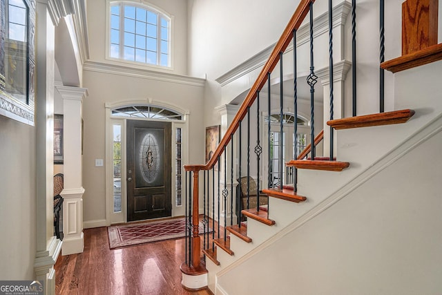 entryway with decorative columns, a high ceiling, a wealth of natural light, and wood finished floors