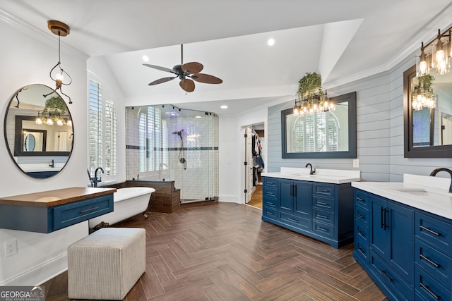 full bath with lofted ceiling, a stall shower, two vanities, and a sink