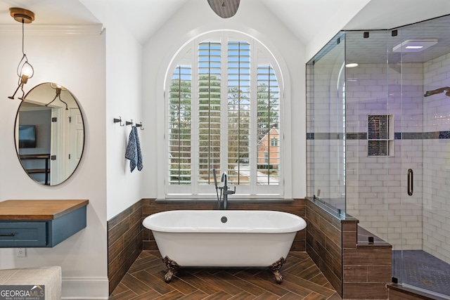 full bath featuring a freestanding tub, a shower stall, vaulted ceiling, and wainscoting