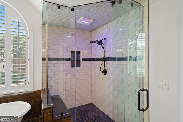 bathroom with a stall shower, a wealth of natural light, and a soaking tub