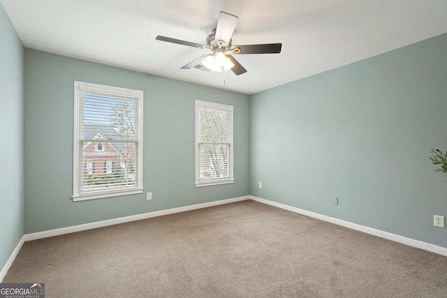 carpeted spare room featuring ceiling fan and baseboards