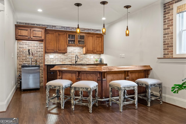 bar featuring decorative light fixtures, crown molding, tasteful backsplash, dark wood-type flooring, and baseboards