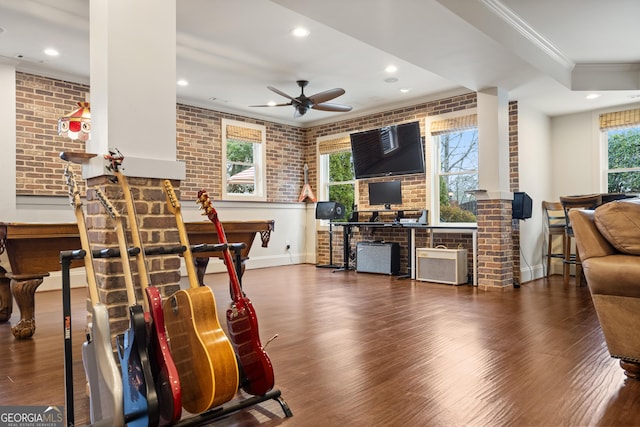 living area with brick wall, ornamental molding, and wood finished floors