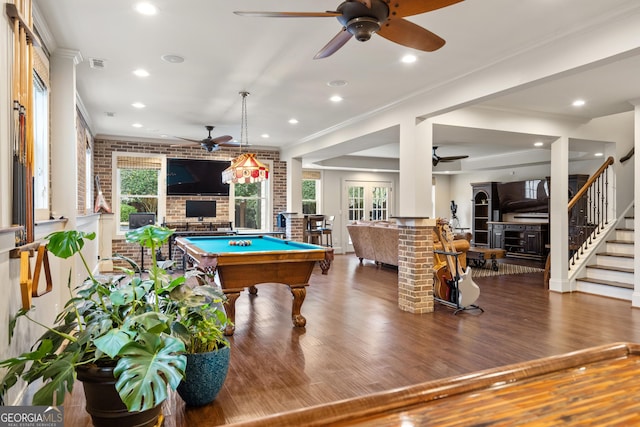 recreation room with brick wall, visible vents, wood finished floors, and ornamental molding