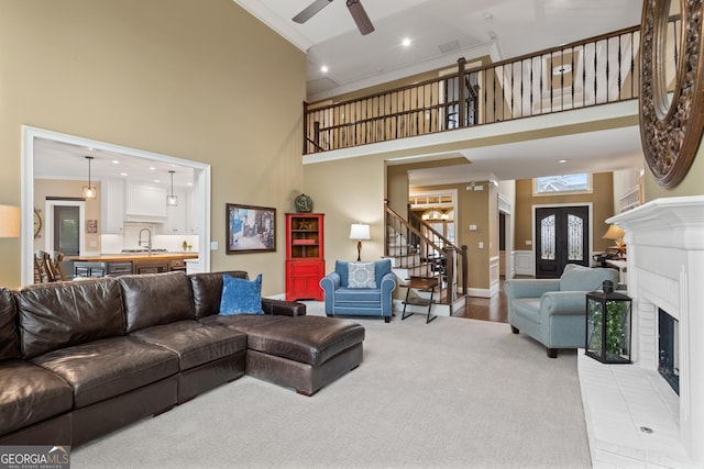 living area with stairway, a fireplace, a towering ceiling, and crown molding