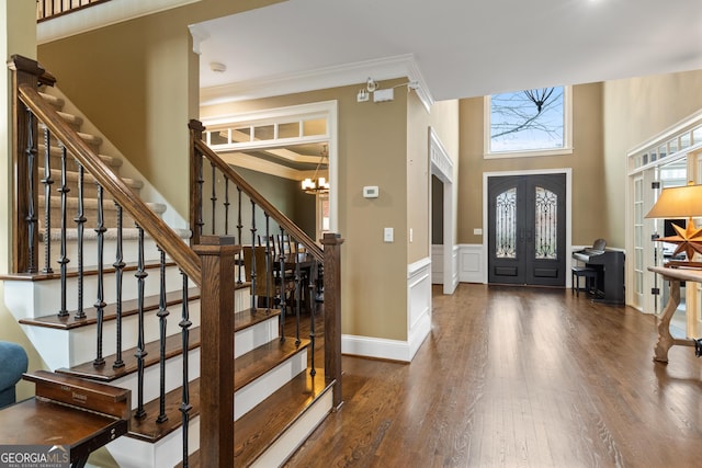 foyer entrance featuring french doors, crown molding, an inviting chandelier, and wood finished floors