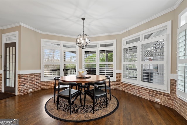 dining space with crown molding, dark wood finished floors, a notable chandelier, and brick wall