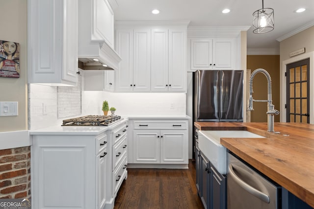 kitchen with stainless steel appliances, a sink, wood counters, white cabinets, and crown molding