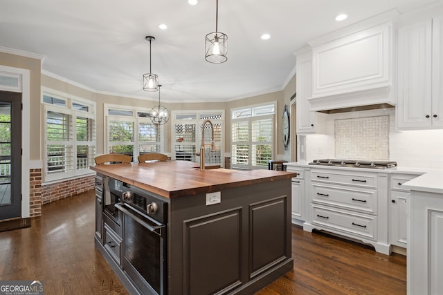 kitchen featuring white cabinets, ornamental molding, stainless steel gas cooktop, wooden counters, and a sink