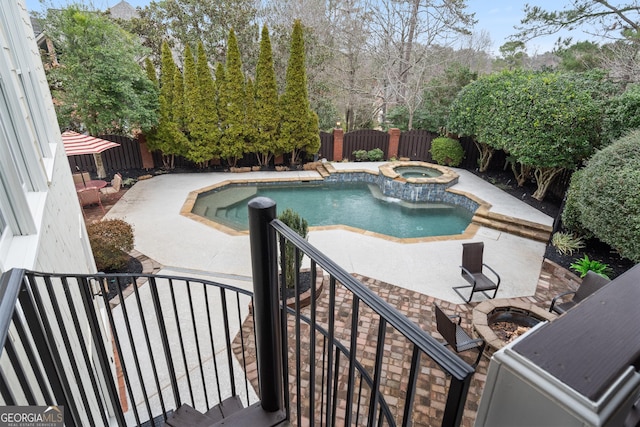 view of swimming pool featuring a fenced backyard, a pool with connected hot tub, and a patio