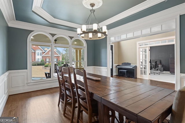 dining space with wainscoting, hardwood / wood-style flooring, crown molding, french doors, and a notable chandelier