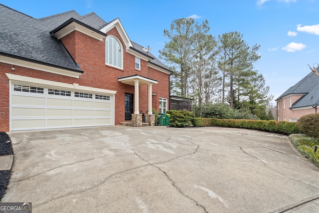 traditional home with a shingled roof, concrete driveway, and brick siding