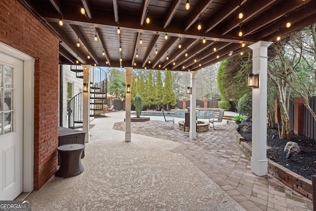 view of patio with an outdoor fire pit, stairway, fence, and a pool with connected hot tub