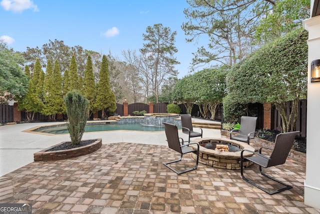 view of patio featuring a pool with connected hot tub, a fenced backyard, and a fire pit