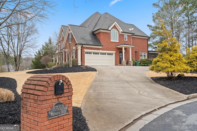 view of front of house featuring driveway, roof with shingles, a garage, and brick siding