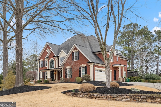 view of front of property with driveway, roof with shingles, a garage, and brick siding