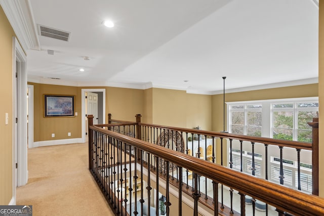 corridor featuring an upstairs landing, visible vents, ornamental molding, and light colored carpet