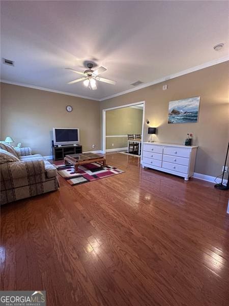 unfurnished living room featuring ceiling fan, visible vents, baseboards, dark wood finished floors, and crown molding