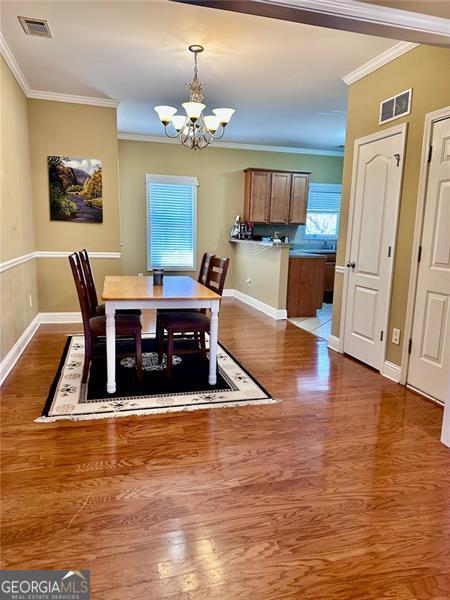 dining area featuring wood finished floors, visible vents, and an inviting chandelier