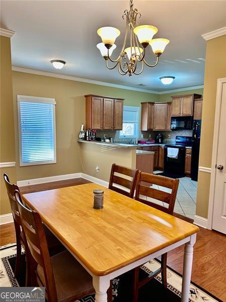 dining space with ornamental molding, a notable chandelier, light wood-style flooring, and baseboards