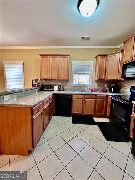 kitchen with a peninsula, black appliances, and brown cabinets