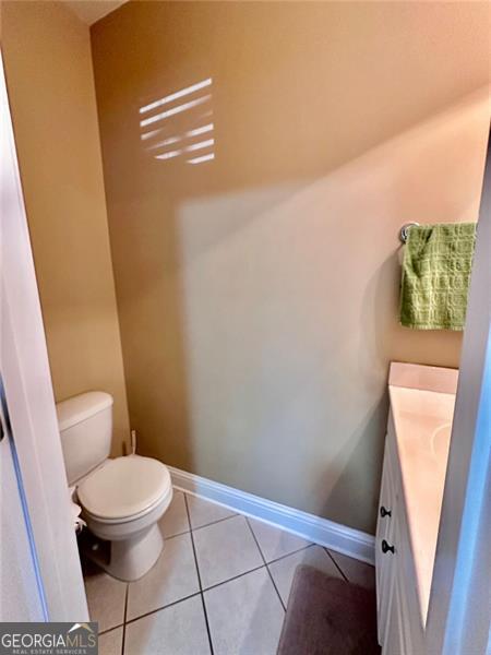 bathroom featuring toilet, vanity, baseboards, and tile patterned floors