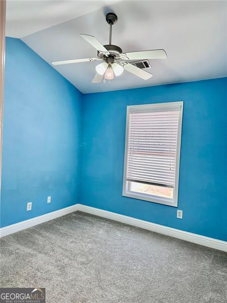 spare room with lofted ceiling, carpet, baseboards, and ceiling fan