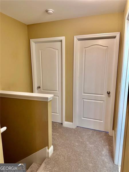 corridor featuring baseboards, light colored carpet, and an upstairs landing