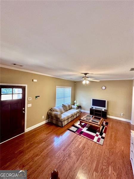 living room with a healthy amount of sunlight, baseboards, wood finished floors, and ornamental molding