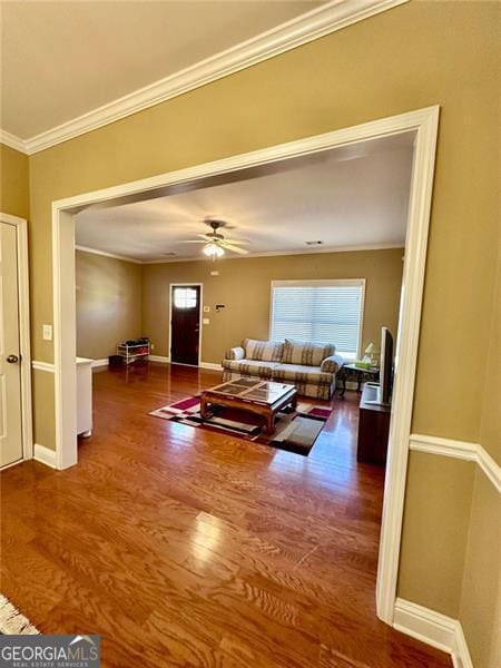 living area with crown molding, plenty of natural light, and wood finished floors