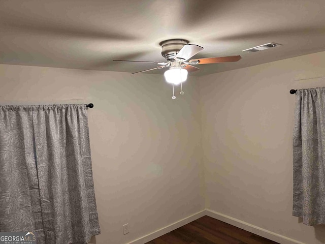 unfurnished room with a ceiling fan, visible vents, baseboards, and wood finished floors