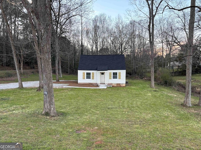 view of front facade with roof with shingles, an outdoor structure, and a front lawn