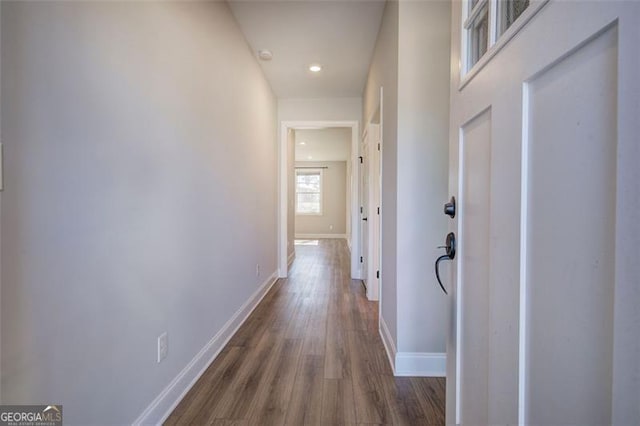 corridor with dark wood-type flooring and baseboards