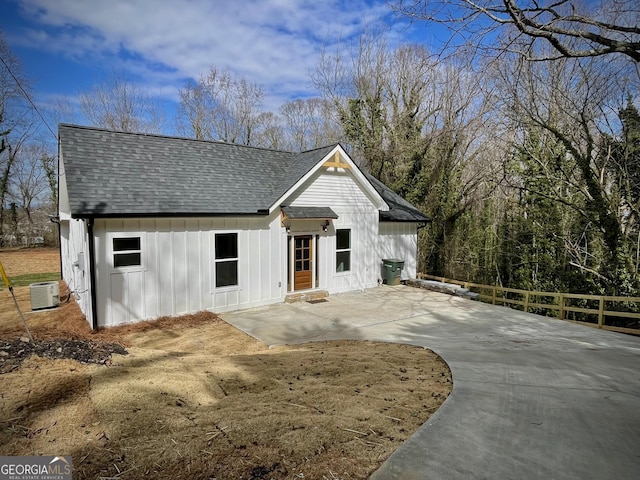 modern inspired farmhouse featuring a shingled roof, a patio area, board and batten siding, and central air condition unit