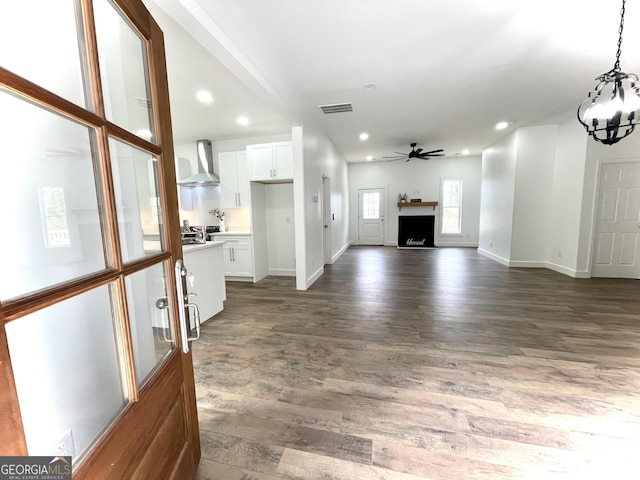 unfurnished living room featuring recessed lighting, visible vents, dark wood finished floors, and ceiling fan with notable chandelier