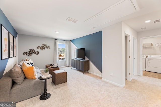 living area with light carpet, attic access, visible vents, and independent washer and dryer