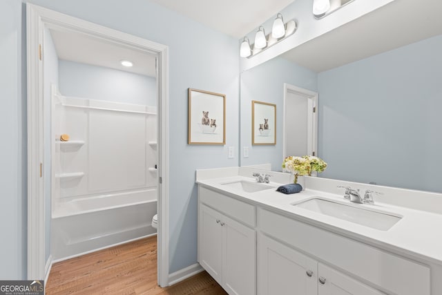 full bath featuring double vanity, toilet, a sink, and wood finished floors