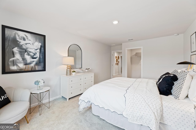 bedroom with a walk in closet, recessed lighting, visible vents, light carpet, and baseboards