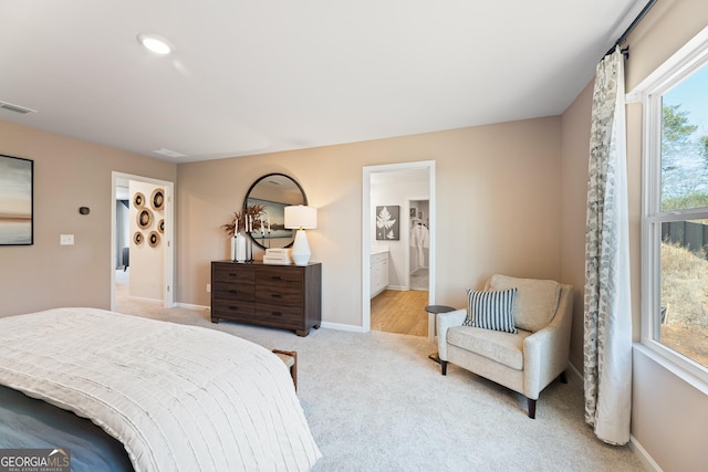 bedroom with baseboards, visible vents, connected bathroom, and light colored carpet