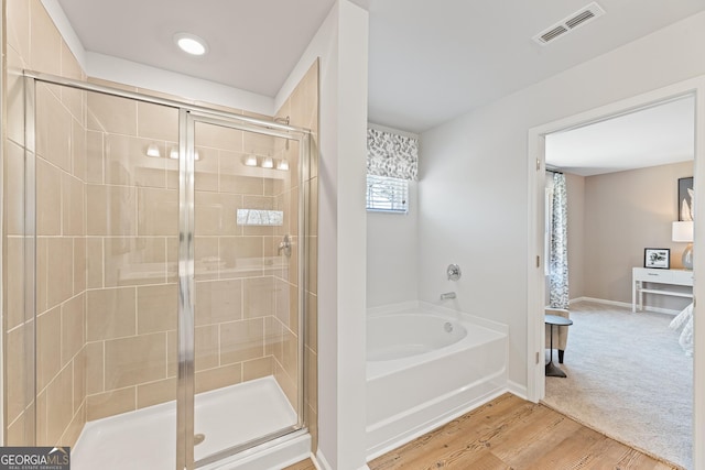 bathroom with baseboards, visible vents, wood finished floors, a shower stall, and a bath