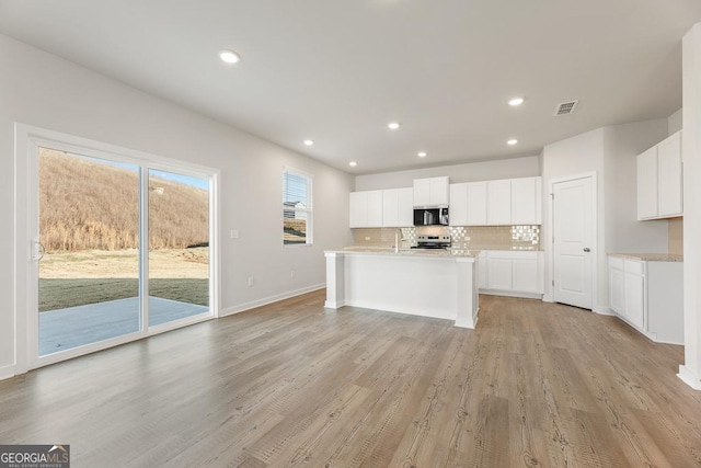 kitchen with tasteful backsplash, light countertops, visible vents, appliances with stainless steel finishes, and white cabinets