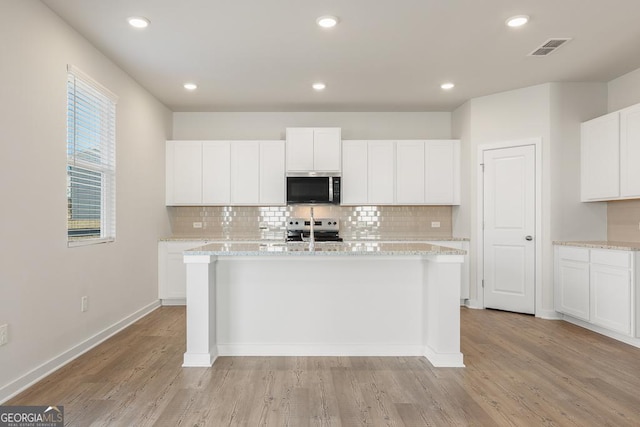 kitchen featuring an island with sink, white cabinetry, visible vents, and appliances with stainless steel finishes